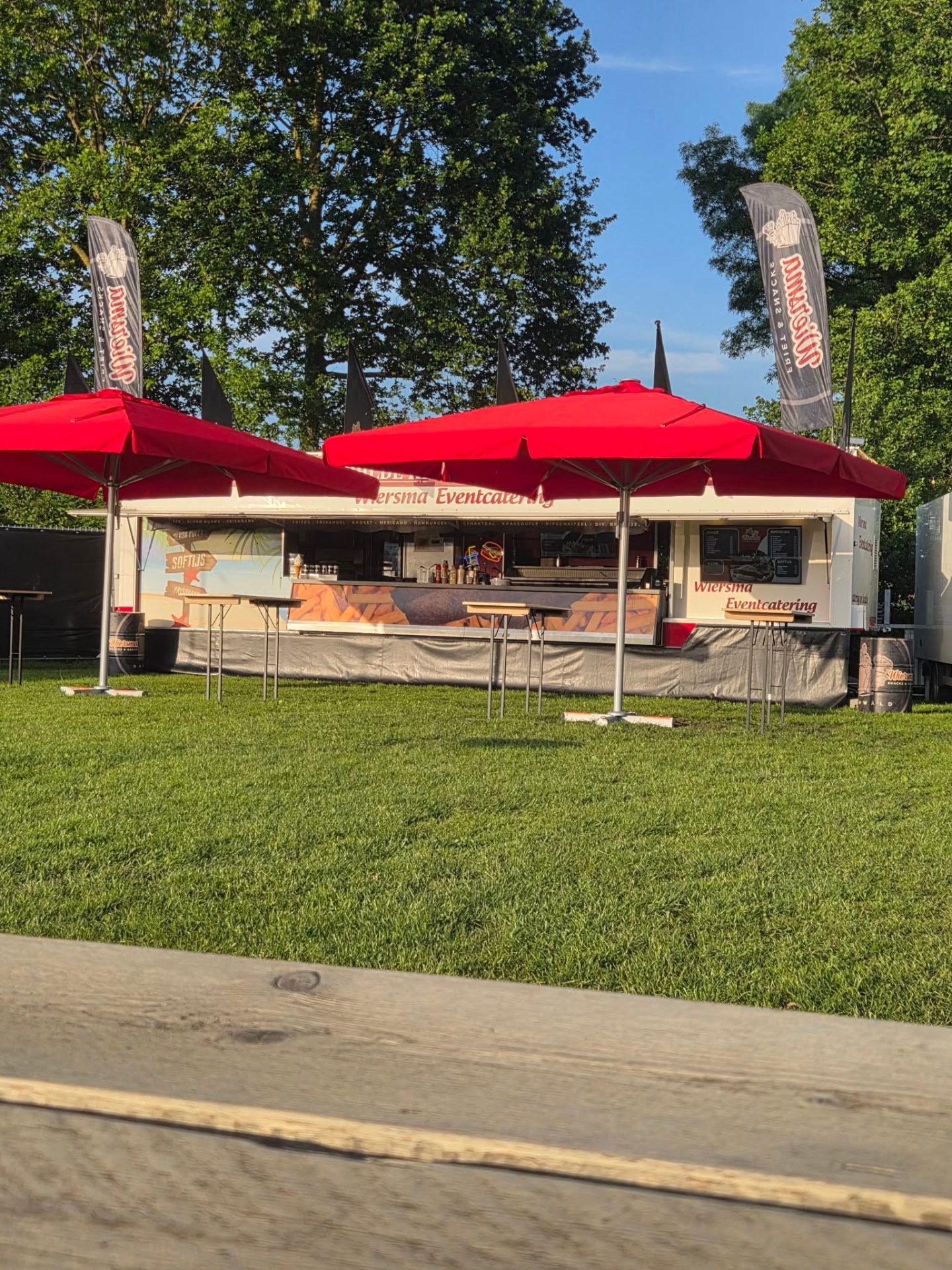 Wiersma Eventcatering kraam met rode parasols op zomerevenement