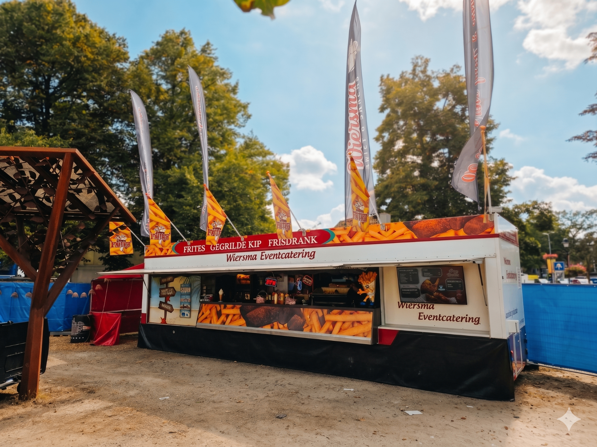 Wiersma snackwagen overdag op een evenement, vlaggen wapperen tegen blauwe lucht