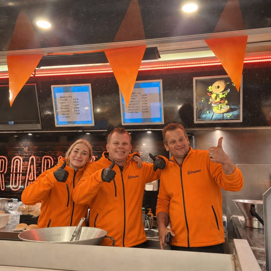Het Wiersma-team met duim omhoog in oranje jas